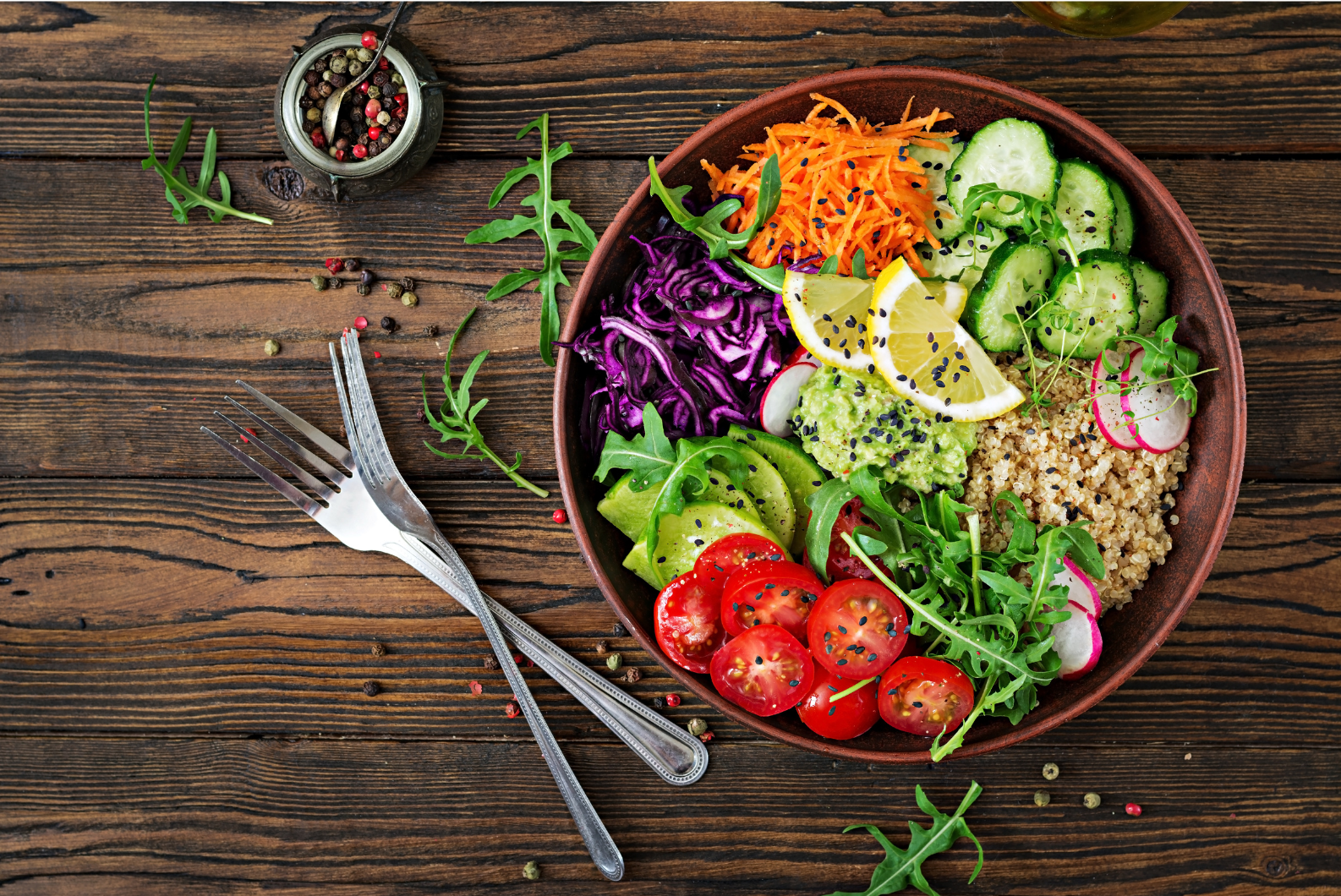 Bol végétarien coloré avec tomates, avocat, quinoa, concombre, chou rouge et citron, sur une table en bois, symbole de la cuisine sans viande du monde.